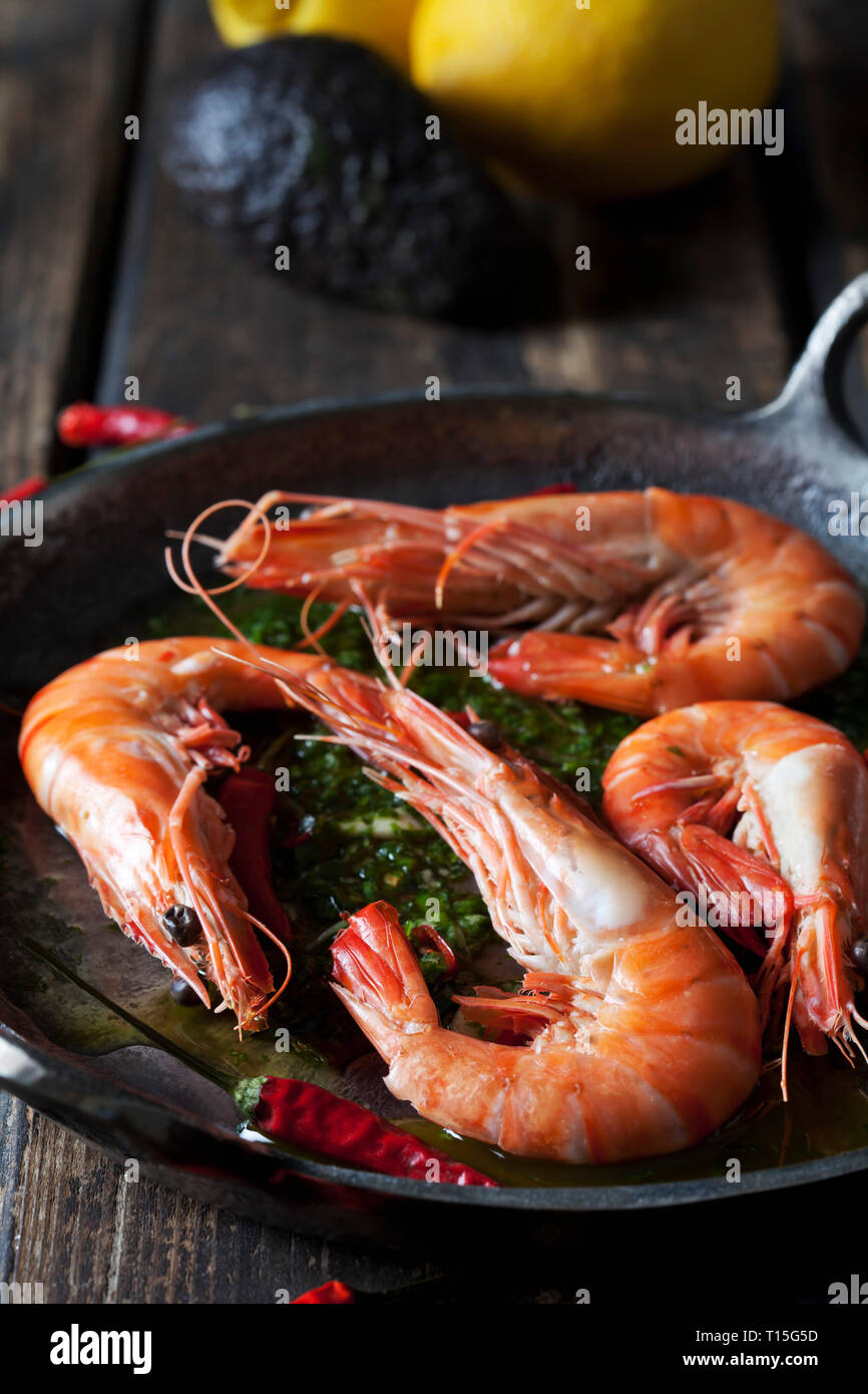 Gamberi con hernbs, peperoncino e aglio in padella di ferro Foto Stock