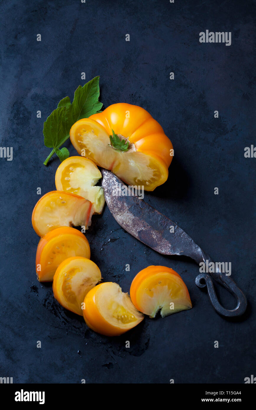 Azoychka a fette di pomodoro e un vecchio coltello sulla terra scura Foto Stock