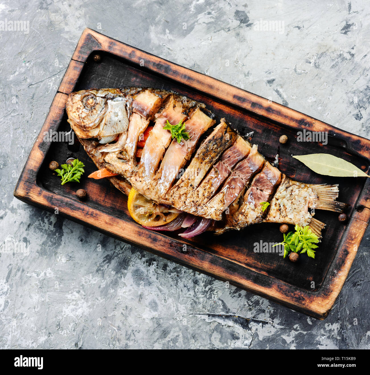 Grigliate di pesce intero con citrus,vegetale e spezie in cucina rustica board.cotte al forno Grigliate di pesce Foto Stock