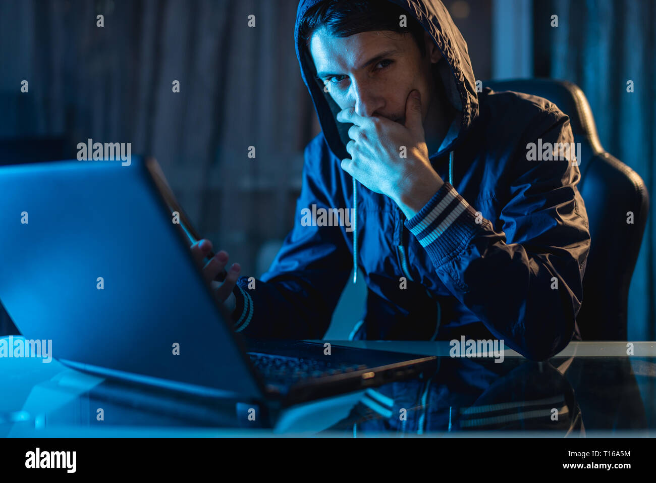 Maschio nel cofano cercando nella fotocamera. Attacchi di hacker e il furto di accedere ai database con password. Il concetto di sicurezza informatica Foto Stock