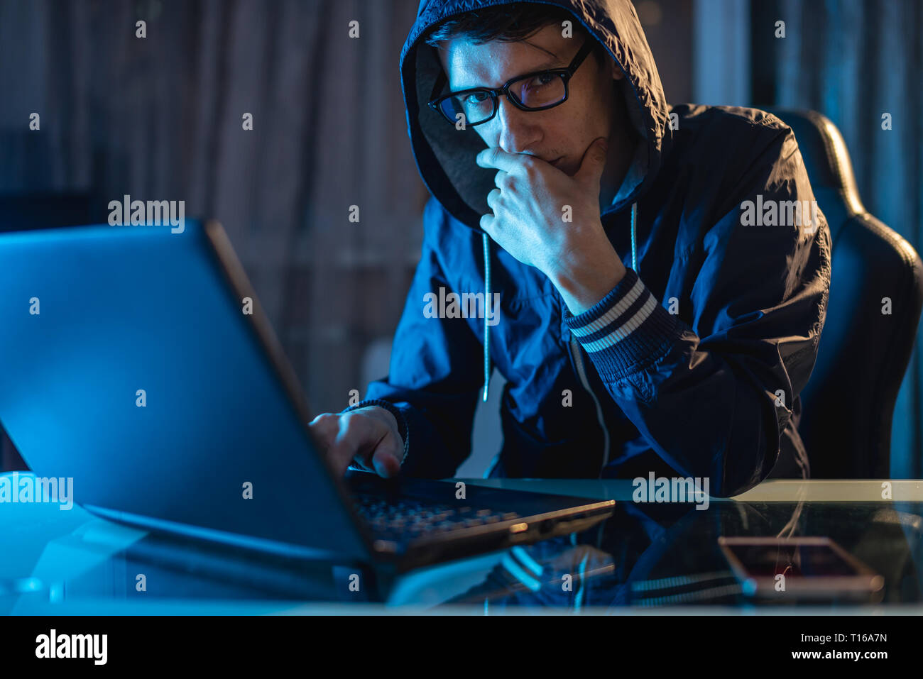 Maschio nel cofano cercando nella fotocamera. Attacchi di hacker e il furto di accedere ai database con password. Il concetto di sicurezza informatica Foto Stock