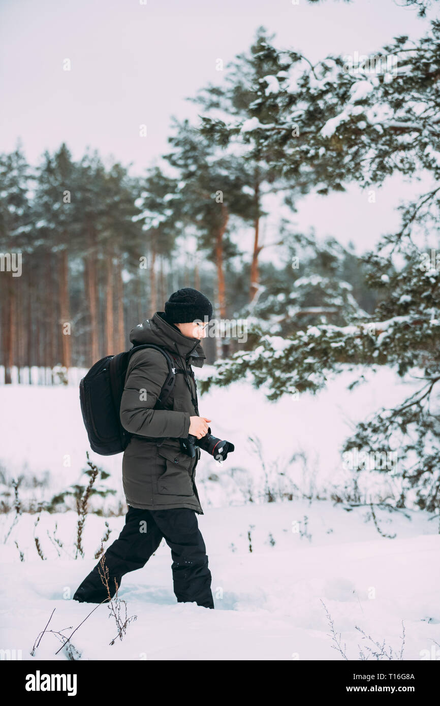 Giovane uomo Backpacker con fotocamera foto tenendo la foto in inverno boschi innevati. Active Hobby. Gli escursionisti a piedi nella neve Pineta Foto Stock
