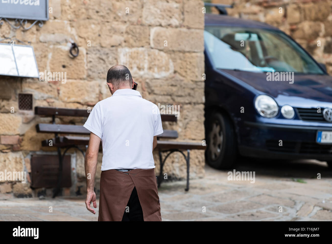 Monticchiello, Italia - 26 agosto 2018: Val d'Orcia in Toscana con cameriere in piccolo villaggio città retro dell uomo a camminare da ristorante Foto Stock