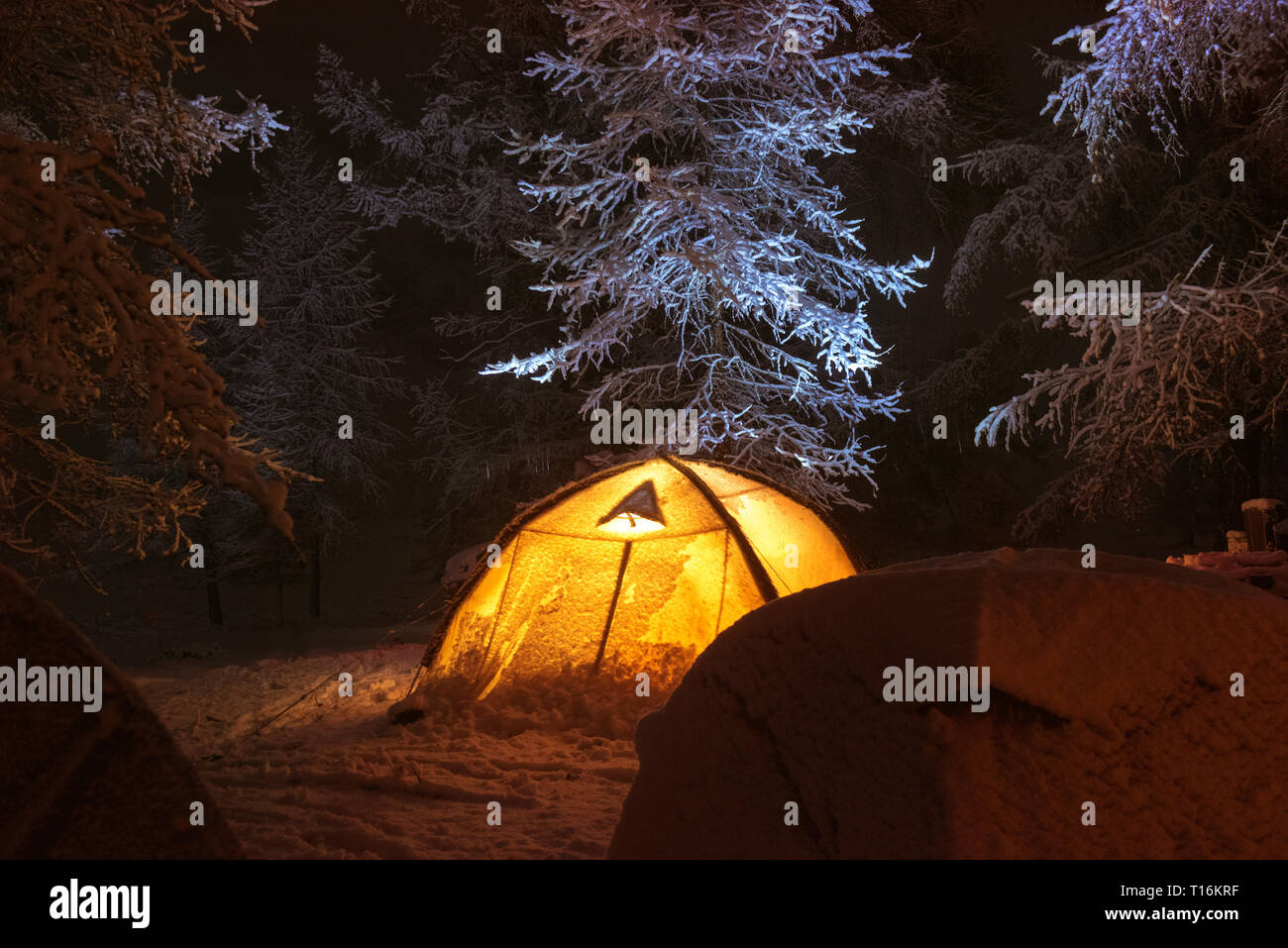 Notte accampamento invernale con gruppo di tende in Snow capped forest Foto Stock