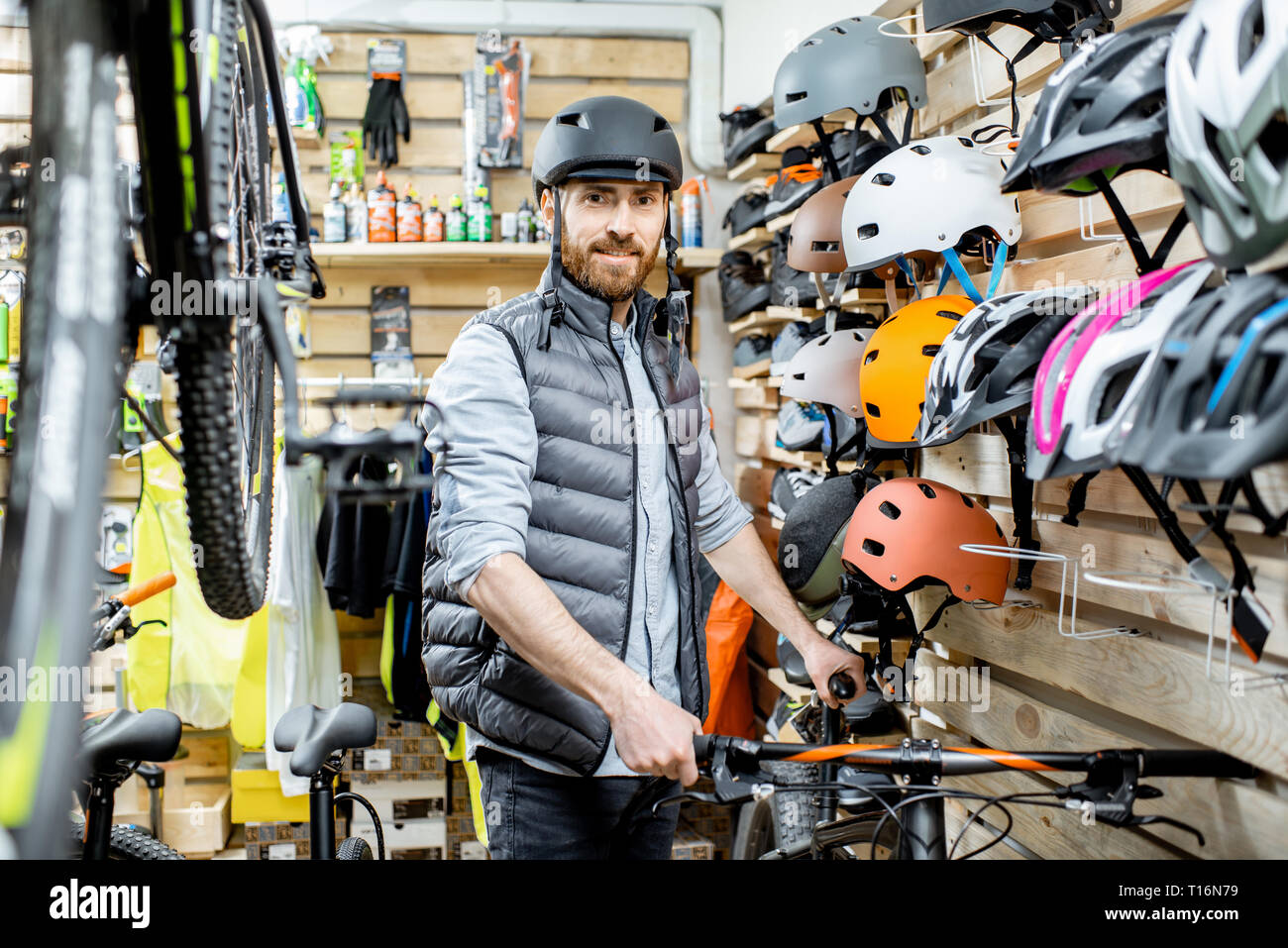 Ritratto di un uomo bello come un acquirente o saleperson bicicletta in piedi vicino al caschi di protezione presso il negozio di biciclette Foto Stock