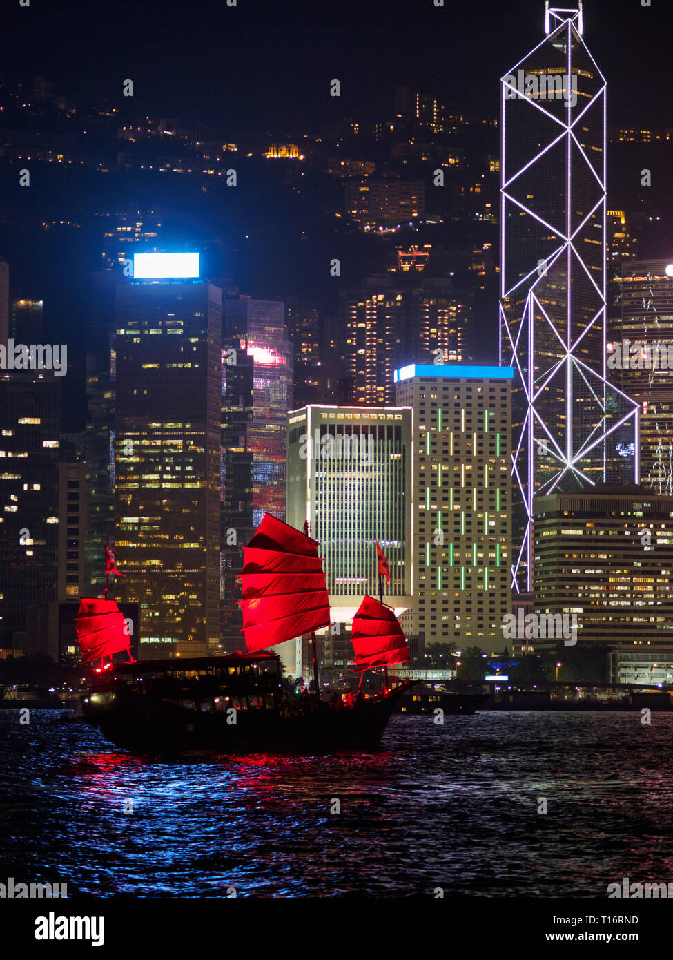 Skyline di Hong Kong in serata con una barca di posta indesiderata in primo piano. Foto Stock