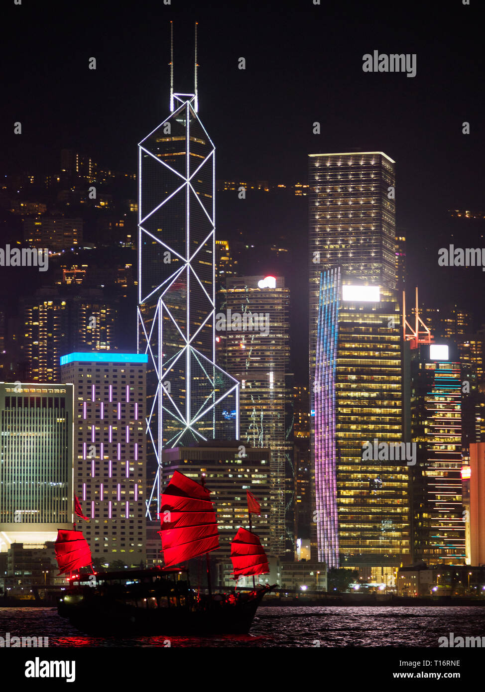 Skyline di Hong Kong in serata con una barca di posta indesiderata in primo piano. Foto Stock