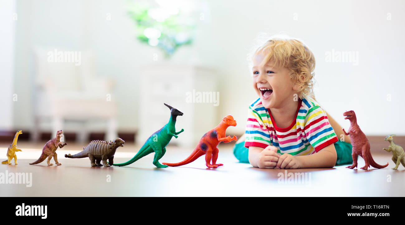 Bambini che giocano con variopinti dinosauri giocattolo. Giocattoli educativi per i bambini. Little Boy learning fossili e rettili. I bambini giocano con i giocattoli di dinosauri. Evol Foto Stock