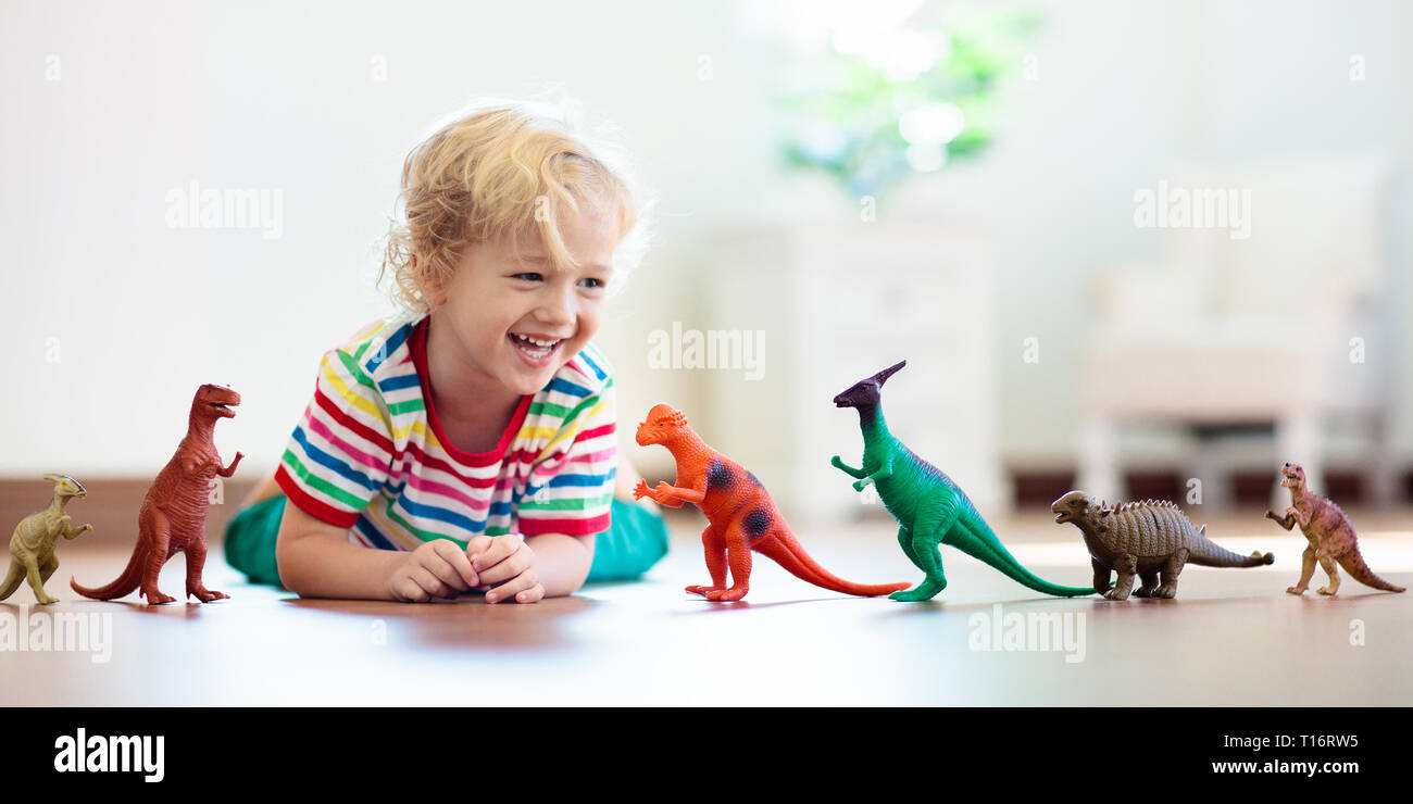 Bambini che giocano con variopinti dinosauri giocattolo. Giocattoli educativi per i bambini. Little Boy learning fossili e rettili. I bambini giocano con i giocattoli di dinosauri. Evol Foto Stock