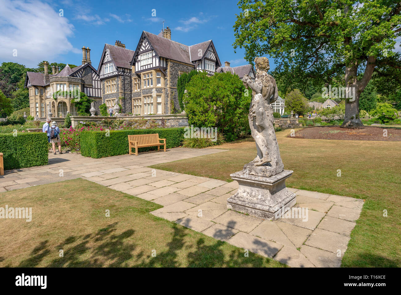 Statua classica guardando verso Bodnant Hall e due visitatori, Bodnant garden, Conwy, Wales, Regno Unito Foto Stock