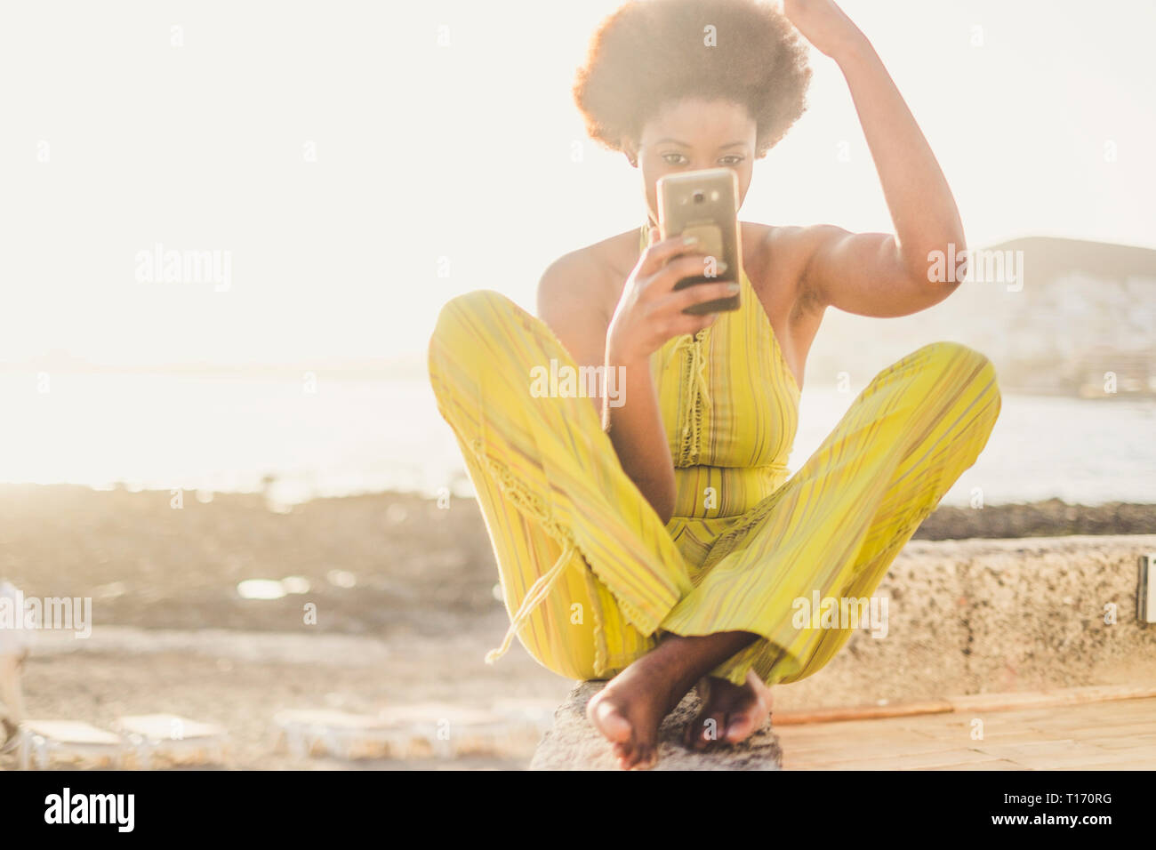 Giovani belle diverse millenario africano nero ragazza utilizzare il telefono moderno come uno specchio per controllare la sua bellezza e make up e capelli - moda donna con Foto Stock
