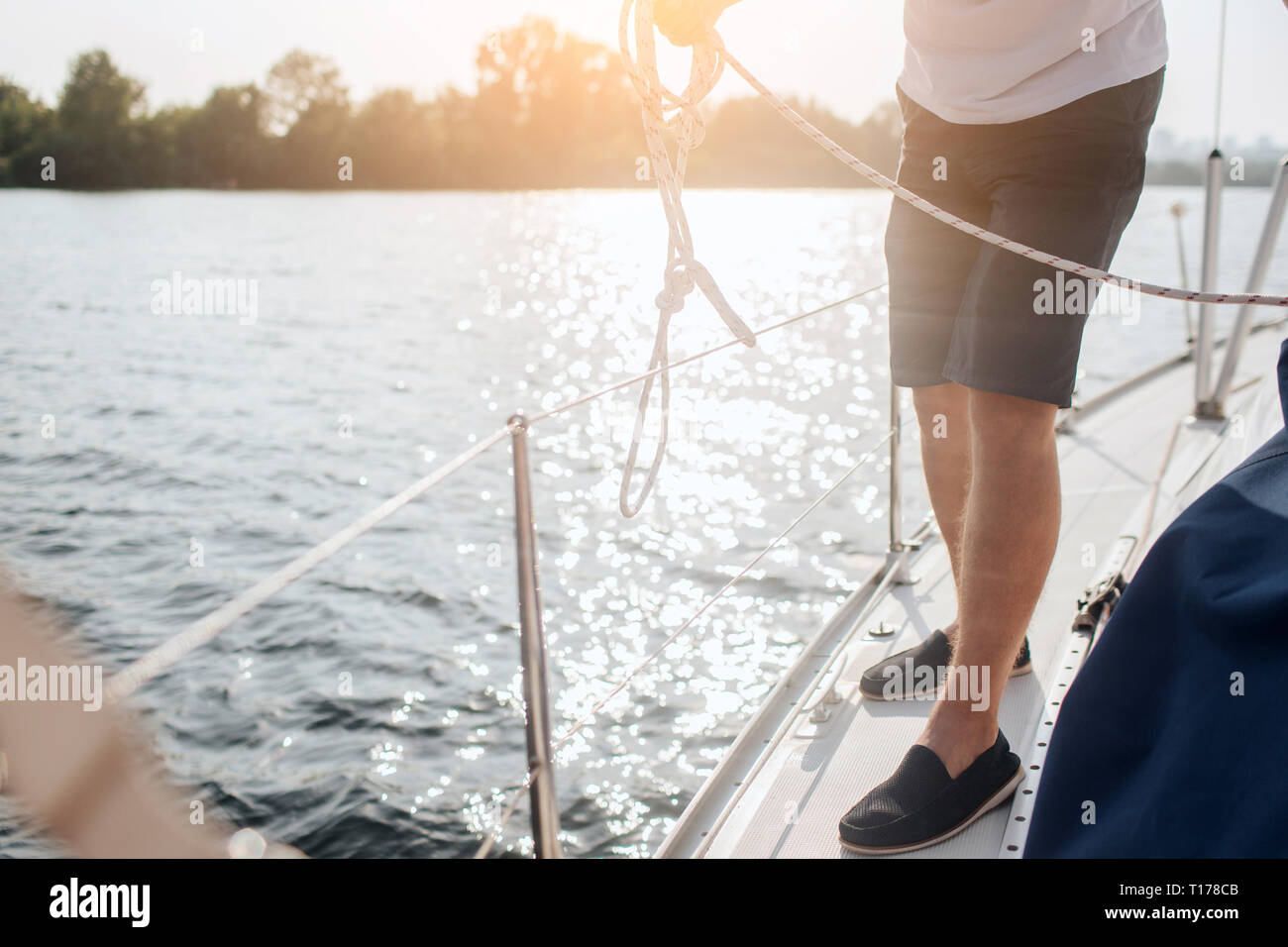 Vista di taglio di uomo in piedi su yacht. Egli è a bordo di essa. L'uomo bianco tiene la corda. Egli sta lavorando. Foto Stock
