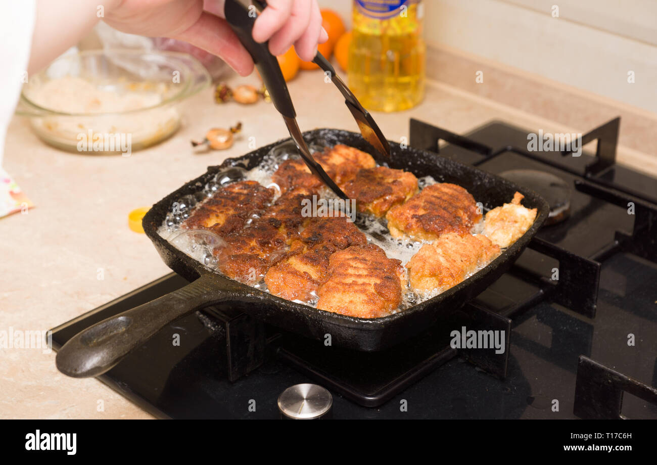 Pepite di cottura da freschi a base di carne di pollo su un caldo cast-padella di ferro Foto Stock