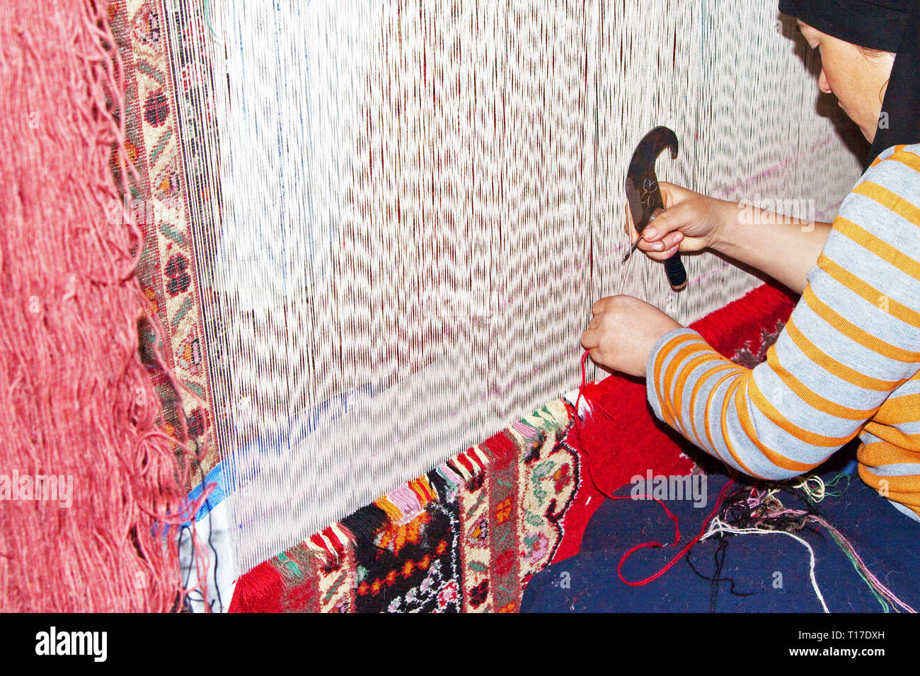 Donna lavora in una fabbrica di tappeti. I tappeti e la seta di Hotan sono stati famosi per migliaia di anni, Hotan, regione autonoma di Xinjiang, Cina. Foto Stock