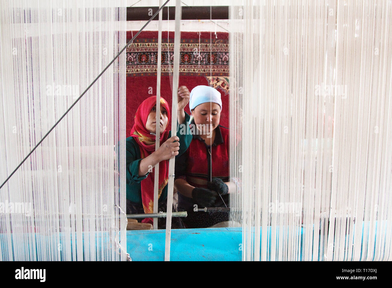 Le donne lavorano in una fabbrica di tappeti. I tappeti e la seta di Hotan sono stati famosi per migliaia di anni, Hotan, regione autonoma di Xinjiang, Cina. Foto Stock