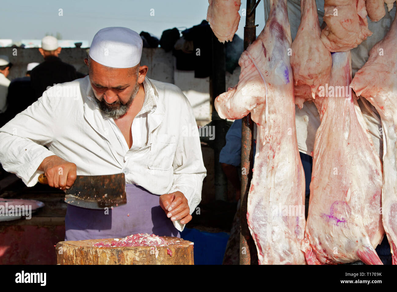 Un macellaio Uighur che lavora al mercato del bestiame della domenica appena fuori Kashgar, regione autonoma di Xinjiang, Cina. Foto Stock