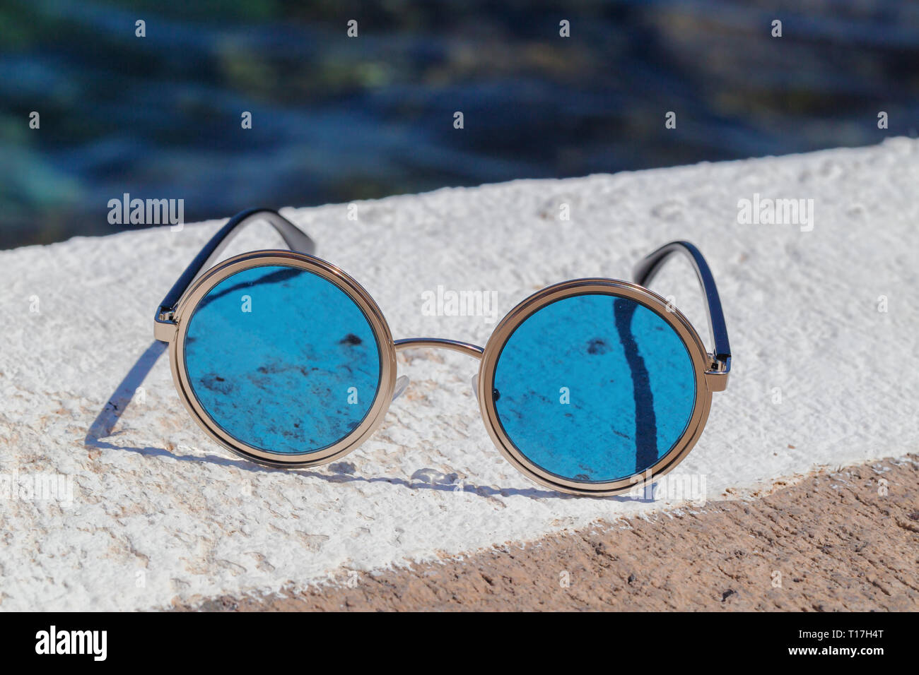 Occhiali da sole rotondi con vetri blu sulla pietra Foto stock - Alamy