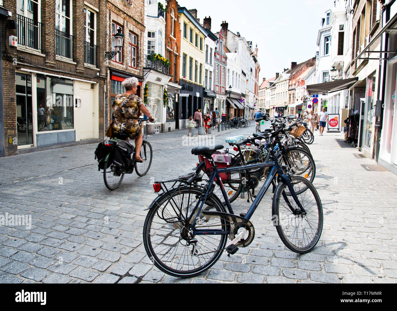 Donna ciclista vista posteriore viaggiando lungo una strada molto pittoresca, brugge, Belgio, Foto Stock