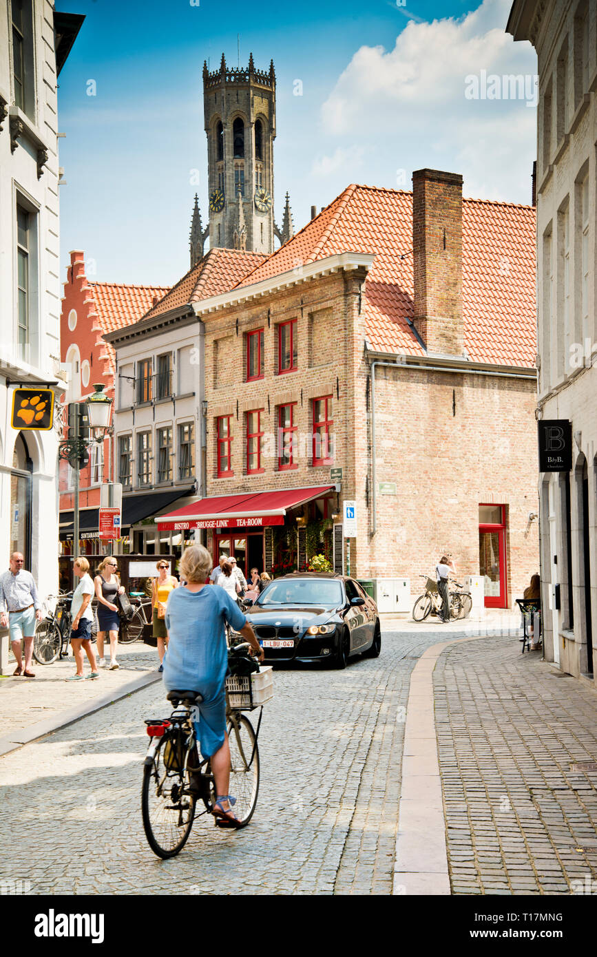 Donna sola in bicicletta verso l'auto in arrivo, piccola strada laterale lontano da macchina fotografica, brugge, Belgio, Europa, Foto Stock