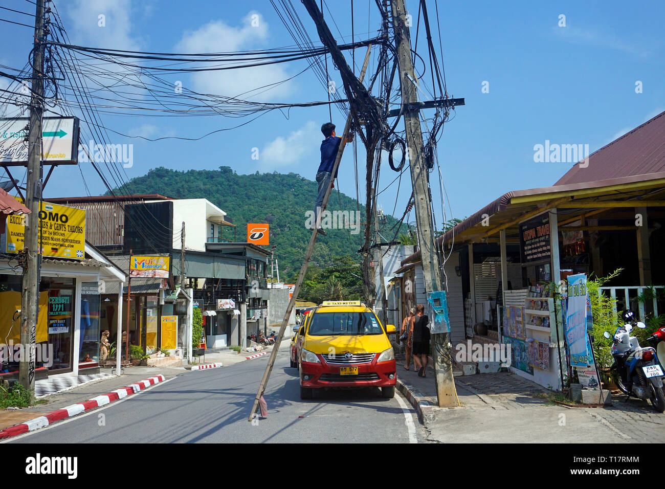 Elettrico si arrampica fino a ledder per riparare alimentatore, downtown, Lamai Beach, Koh Samui, Surat Thani, Golfo di Thailandia, Tailandia Foto Stock
