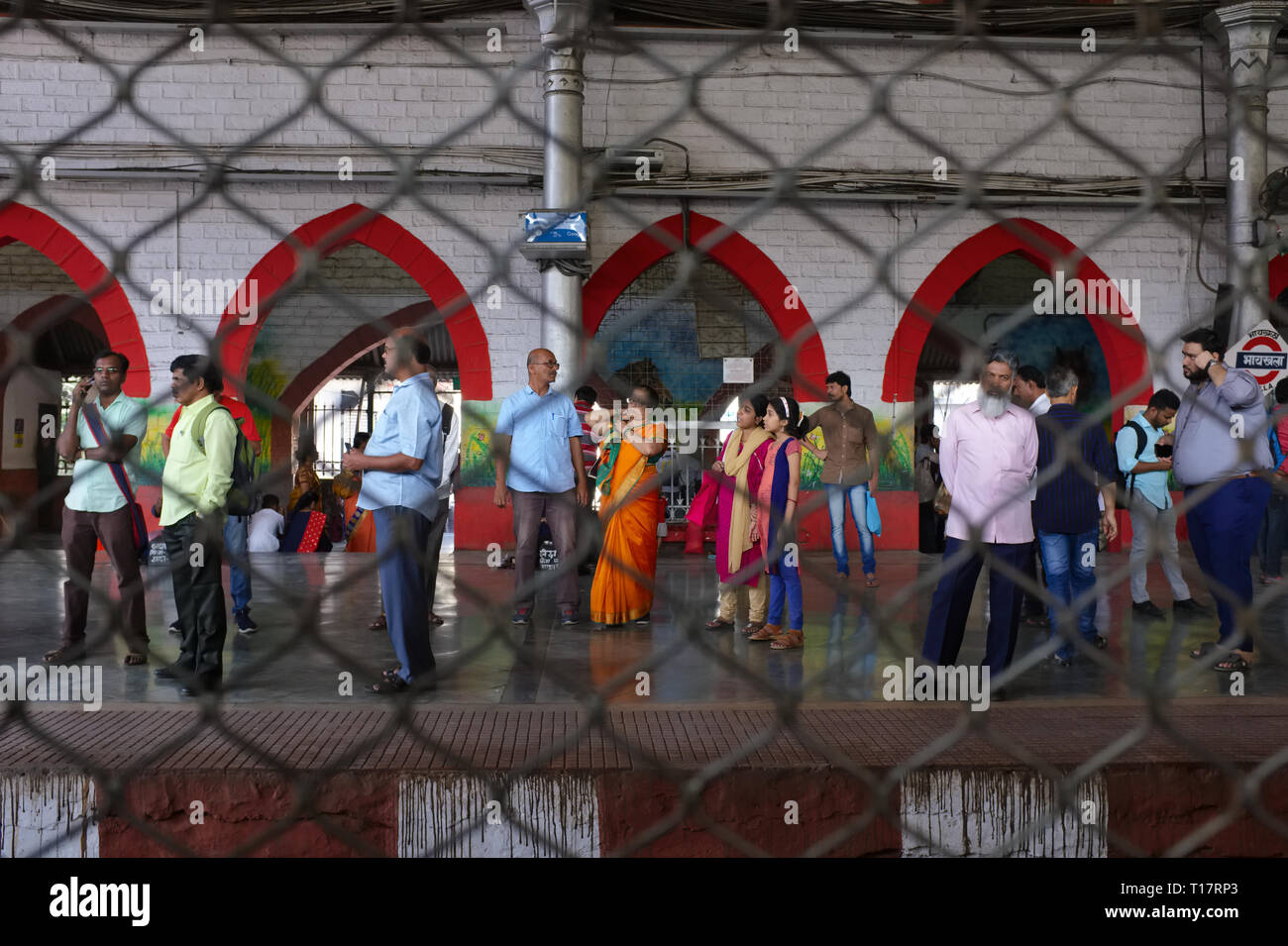 Vista attraverso il filo di maglia nella parte anteriore di un treno passeggeri bogey della finestra in Mumbai, India, verso la piattaforma alla stazione Byculla e passeggeri Foto Stock