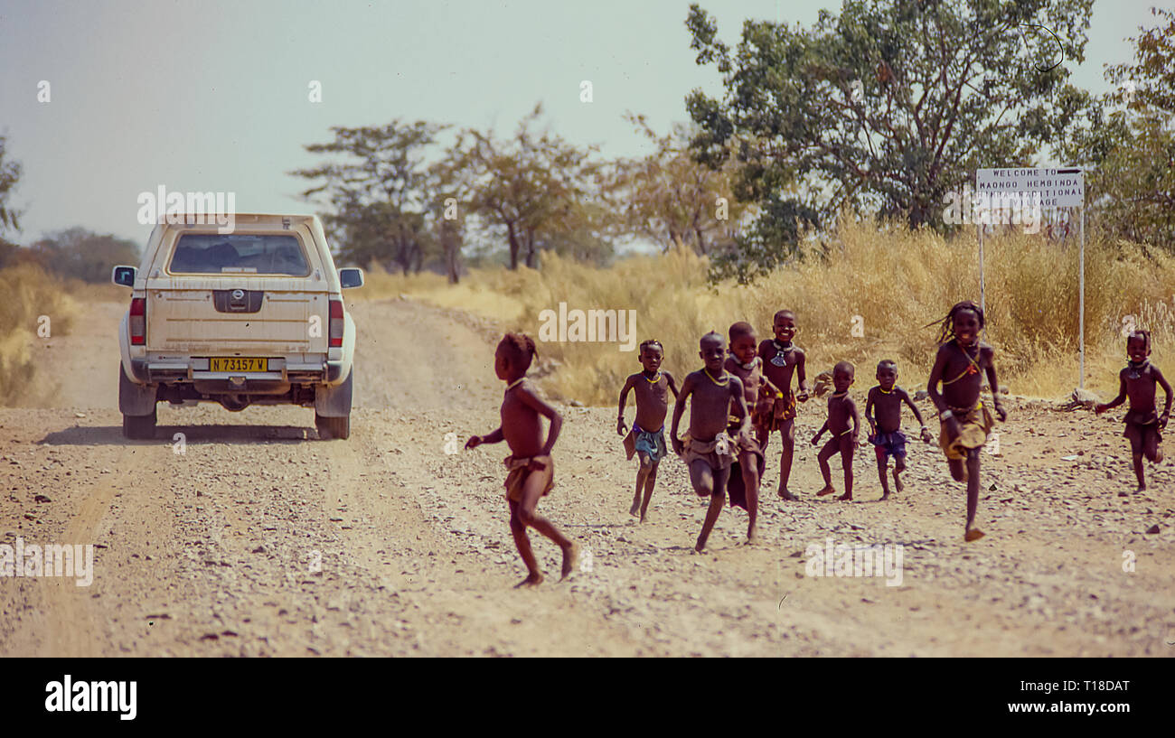 Gruppo di himba i bambini a correre verso il off-road vetture di turisti vicino al Epupa Falls in Namibia Foto Stock