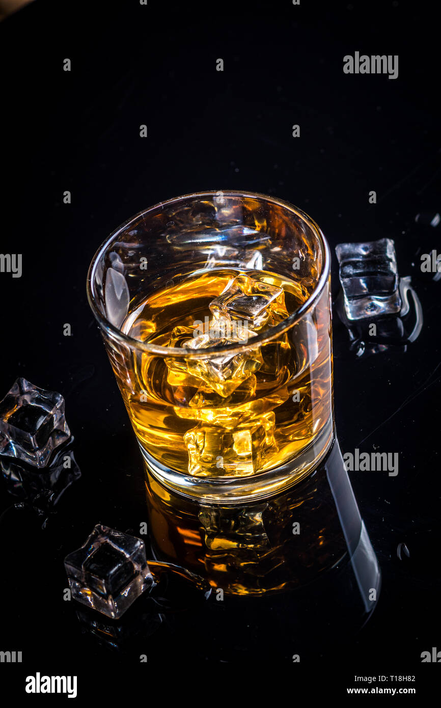Whisky whiskey Bourbon o in vetro con cubetti di ghiaccio nero su sfondo di riflessione Foto Stock