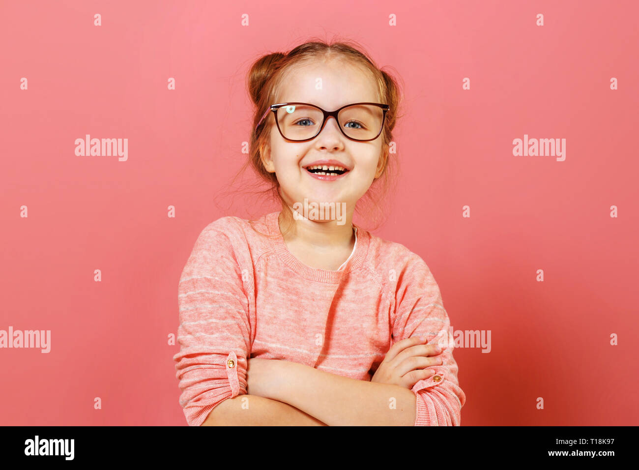 Ritratto di bella carino adorabile Allegro vivace contenuto moderno piccolo bambino ragazza bracci ripiegati in bicchieri su sfondo rosa Foto Stock