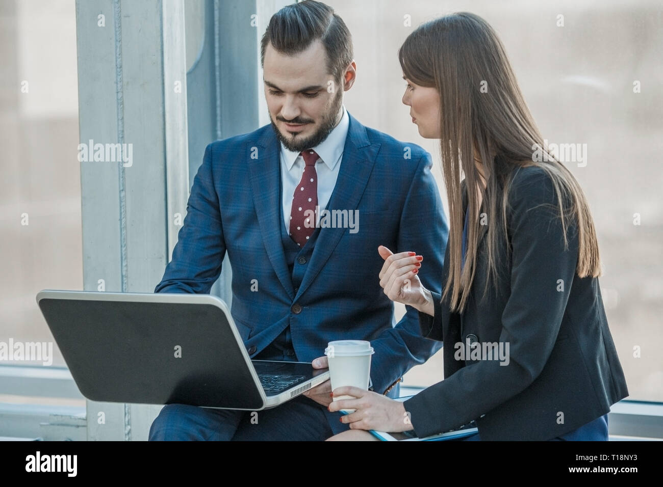 Allegro impiegati a discutere il loro progetto al laptop tramite tazza di caffè Foto Stock