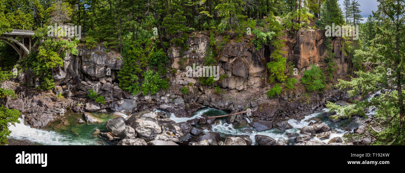 Panorama di un ponte sulla sinistra con un ruscello che corre tra massi in uno stretto canyon scoscesi in una fitta foresta vicino al Fiume di Rogue in Oregon Foto Stock