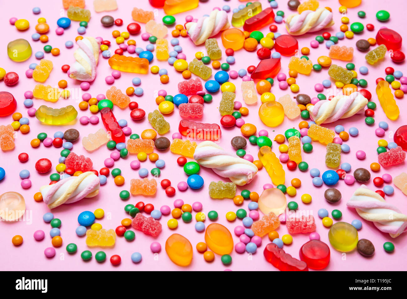 Concetto di compleanno. Colorato assortimento di dolci caramelle sul rosa pastello sfondo, primo piano Foto Stock