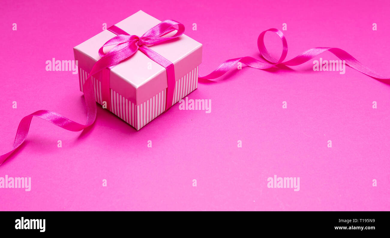 Rosa confezione regalo. Presente con nastro rosa sulla prua rosa luminoso dello sfondo. Womens o madri giorno concetto. Foto Stock