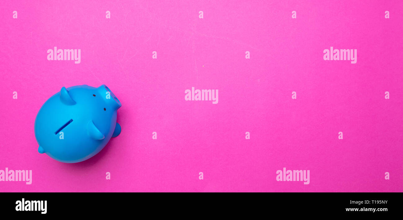 Il concetto di risparmio. Salvadanaio di colore blu brillante contro sfondo rosa, banner, copia spazio, vista dall'alto. Foto Stock