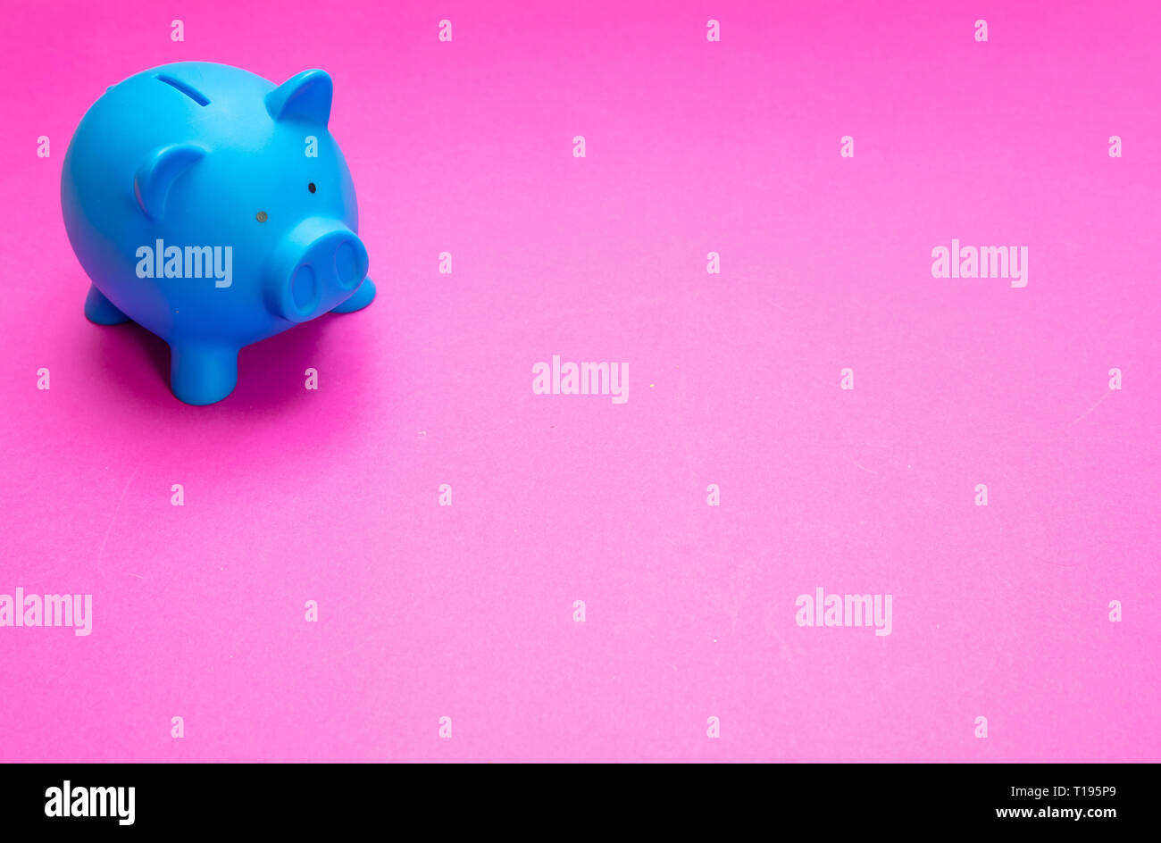 Il concetto di risparmio. Salvadanaio di colore blu brillante contro sfondo rosa, copia dello spazio. Foto Stock