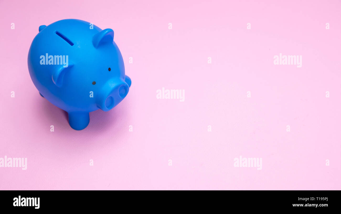 Il concetto di risparmio. Salvadanaio di colore blu pastello contro sfondo rosa, copia dello spazio. Foto Stock