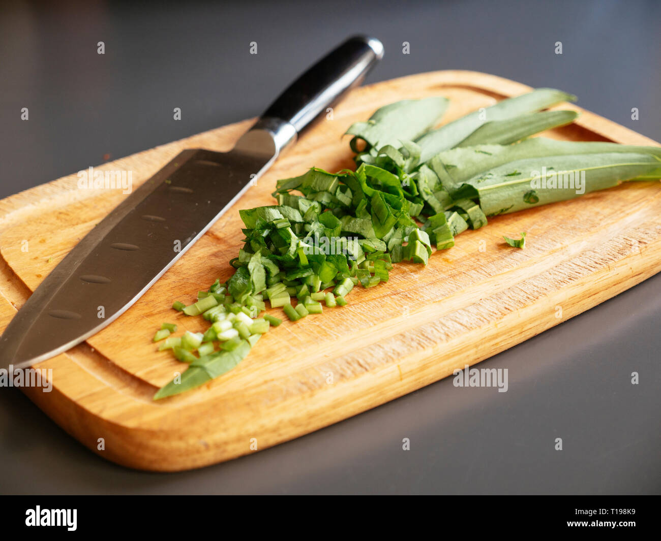 Un trito di aglio selvatico su un tagliere. Foto Stock