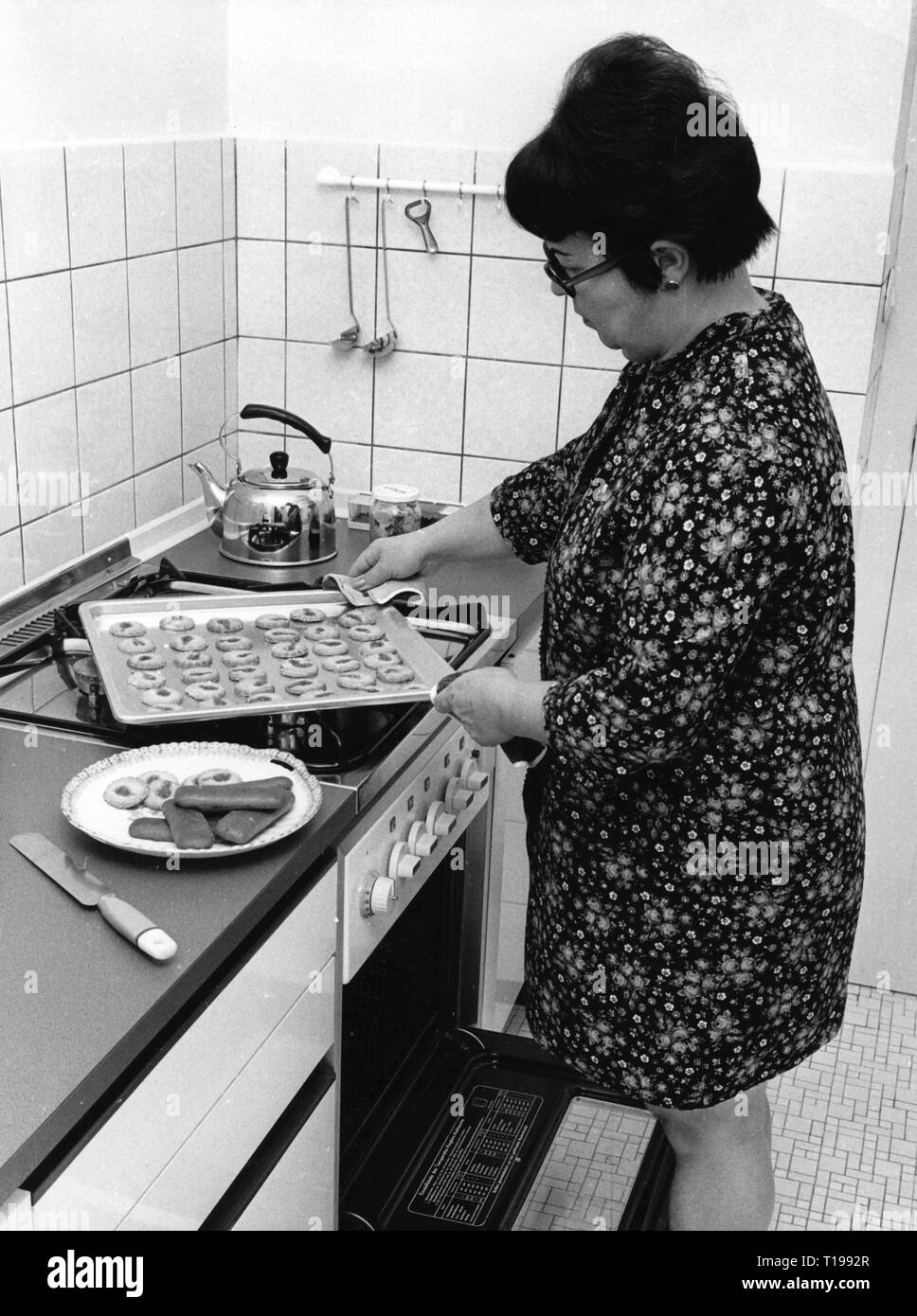 Domestico, cucina e panificazione, casalinga prendendo i biscotti di Natale al di fuori del forno, 1970, Additional-Rights-Clearance-Info-Not-Available Foto Stock