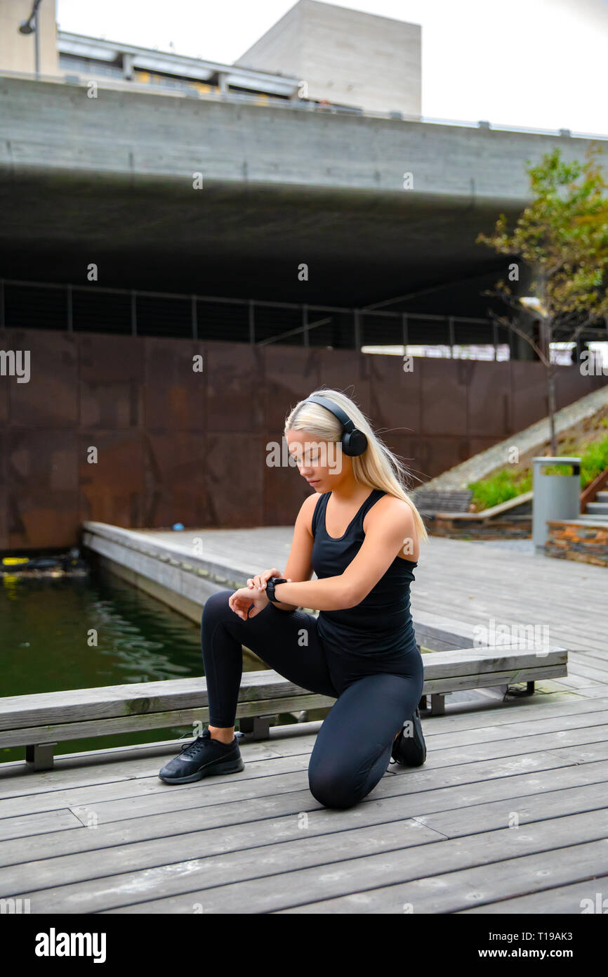 Sportivo da donna ascoltando musica e utilizzando Smartwatch prima dell'esecuzione Foto Stock