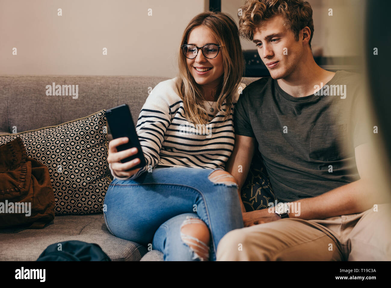 Due studenti del college tenendo selfie con un telefono cellulare al college campus. Giovane uomo e donna seduta sul divano tenendo un autoritratto con il telefono cellulare. Foto Stock