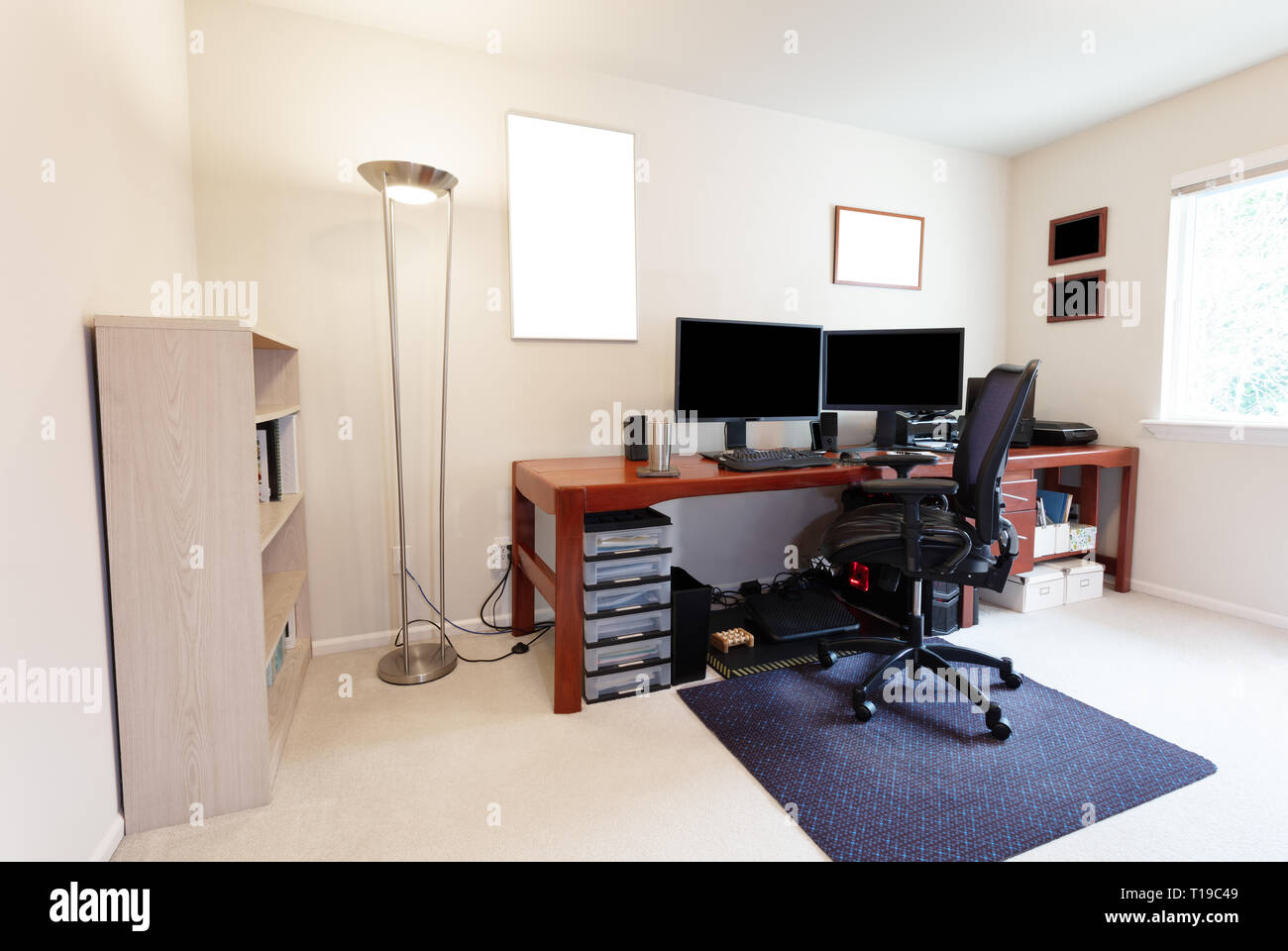 Calcolatore confortevole sedia al grande tavolo di lavoro con monitor di computer e altre apparecchiature tecnologiche in bright home office interno Foto Stock