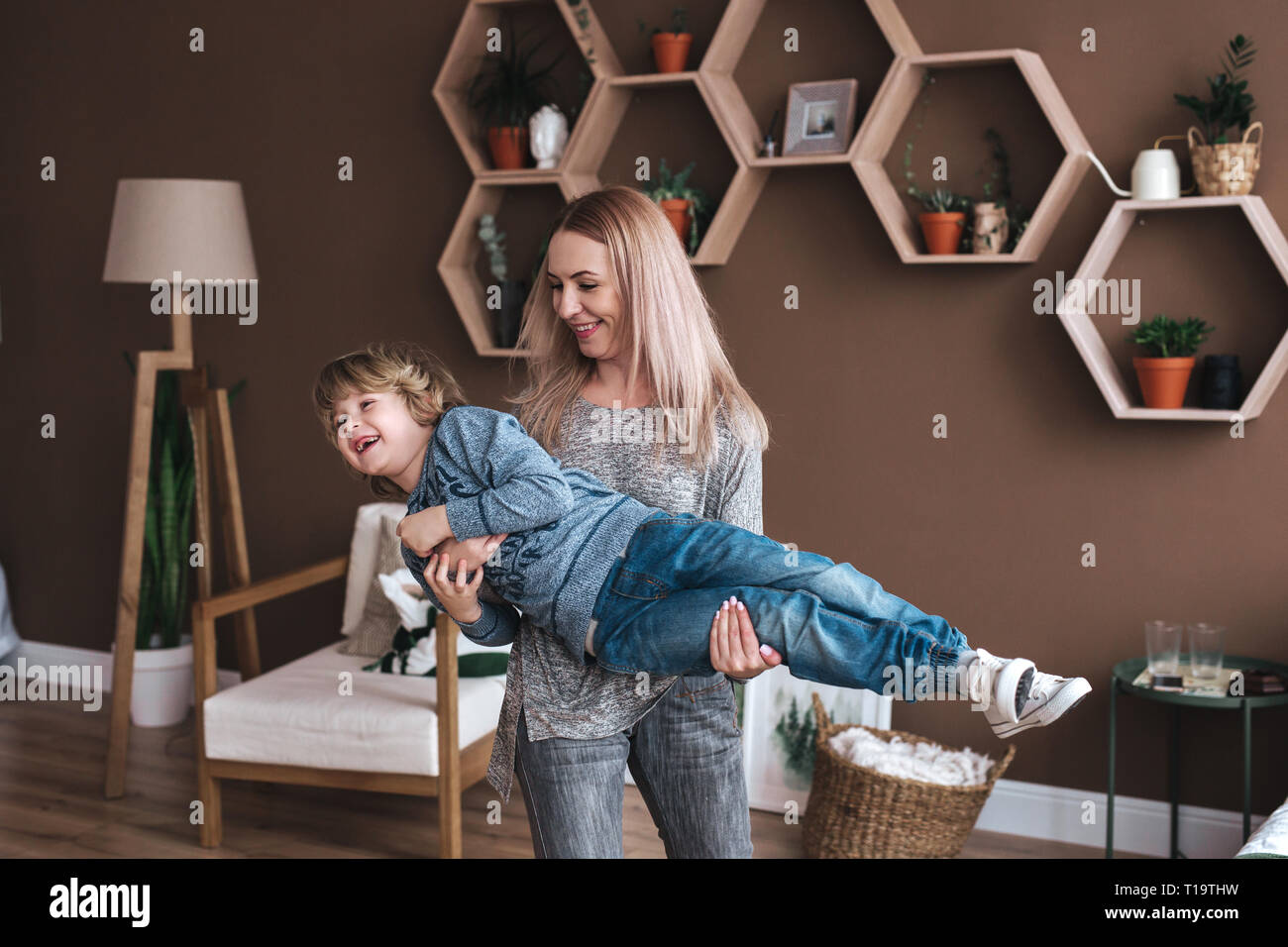 Allegro ragazzino divertendosi con la madre sul divano Foto Stock