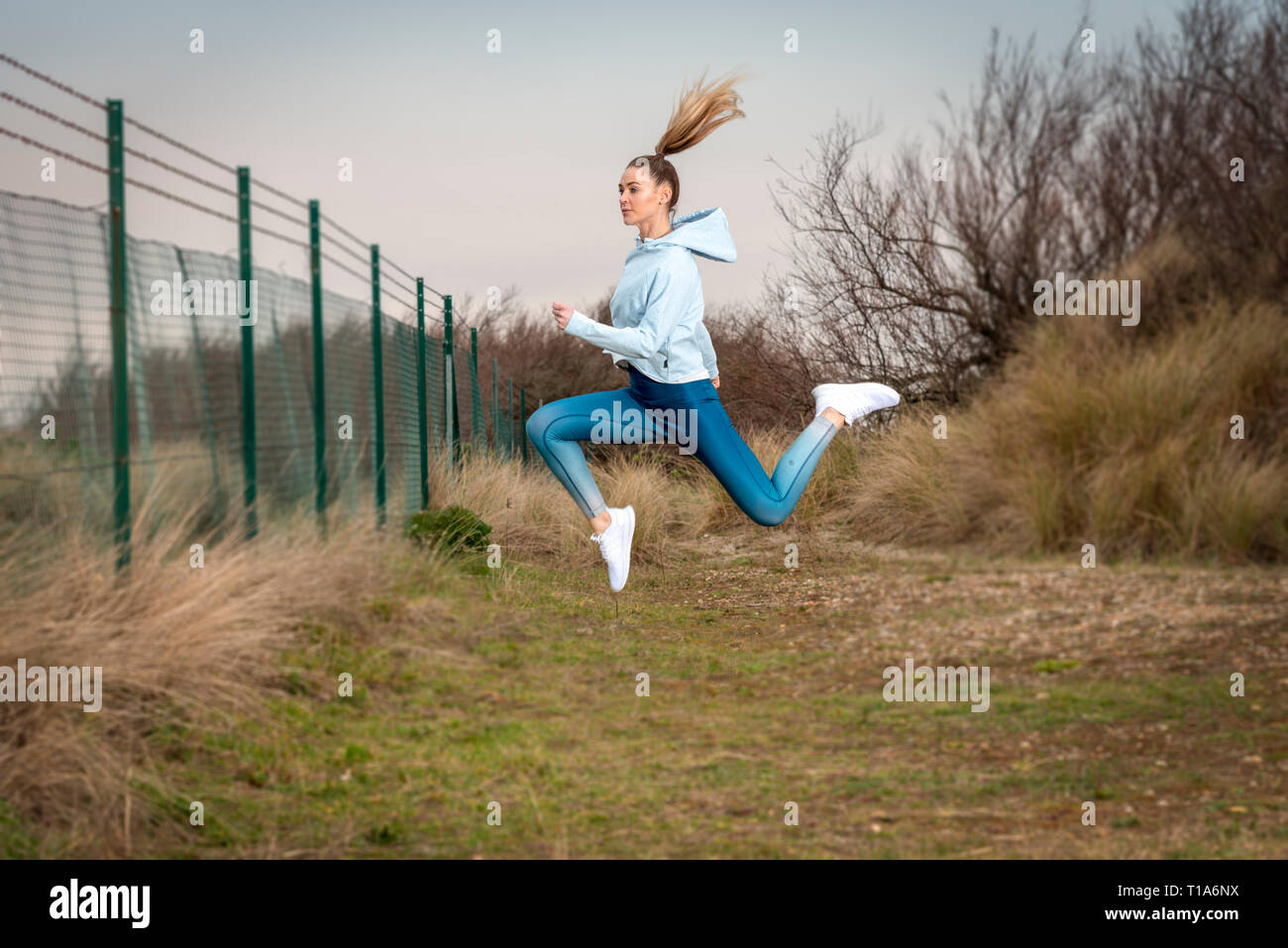 La donna in esecuzione al di fuori, saltando in aria. Foto Stock