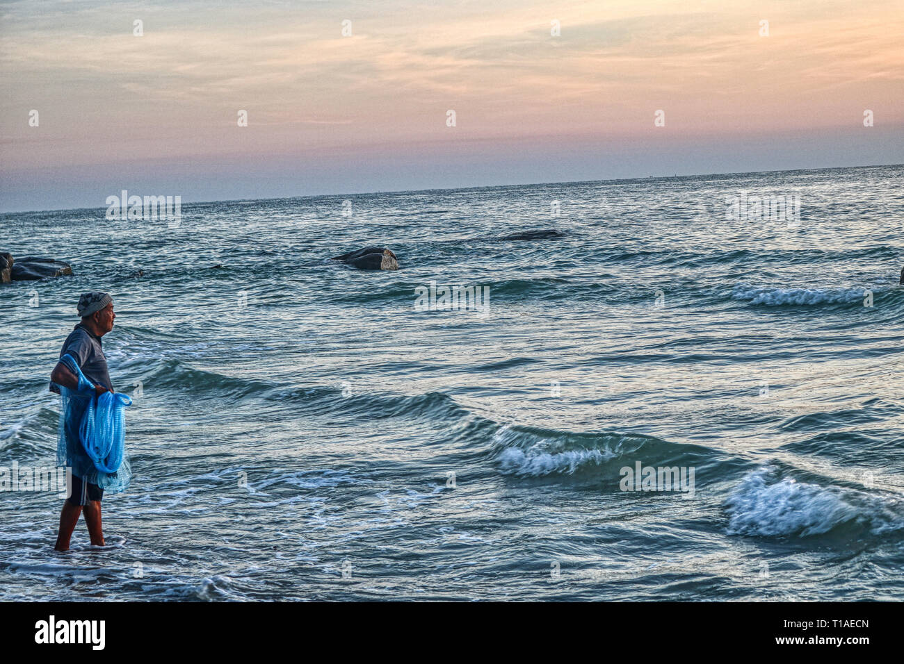 Questa grande mostra fotografica Il sunrise di Hua Hin in Thailandia la mattina presto a sunrise. In piedi in mare, si può vedere un pescatore di cattura di pesce Foto Stock