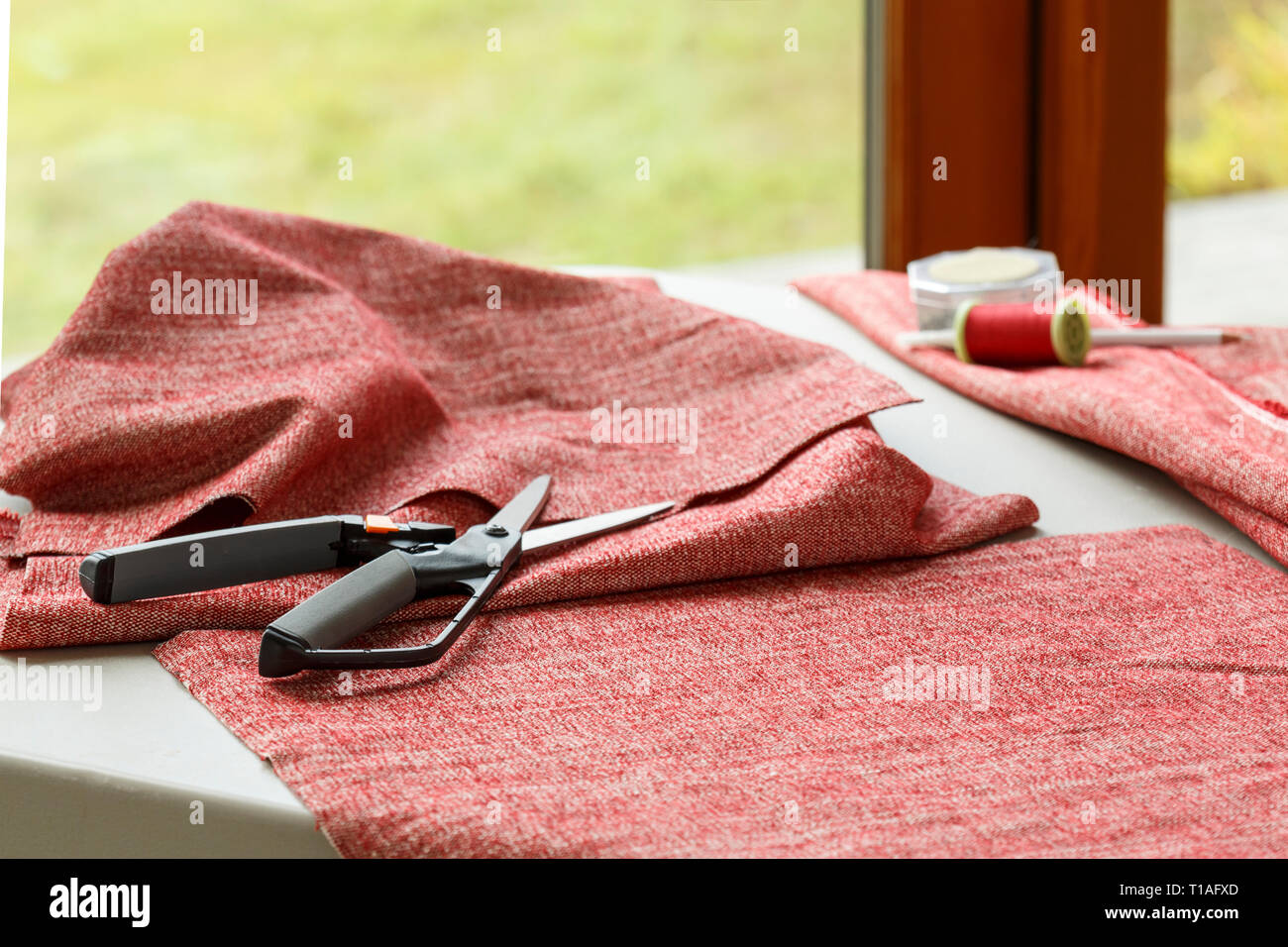 Home cucire bricolage hobby. Tessuto tessuto, forbici e filettatura sul tavolo. Foto Stock