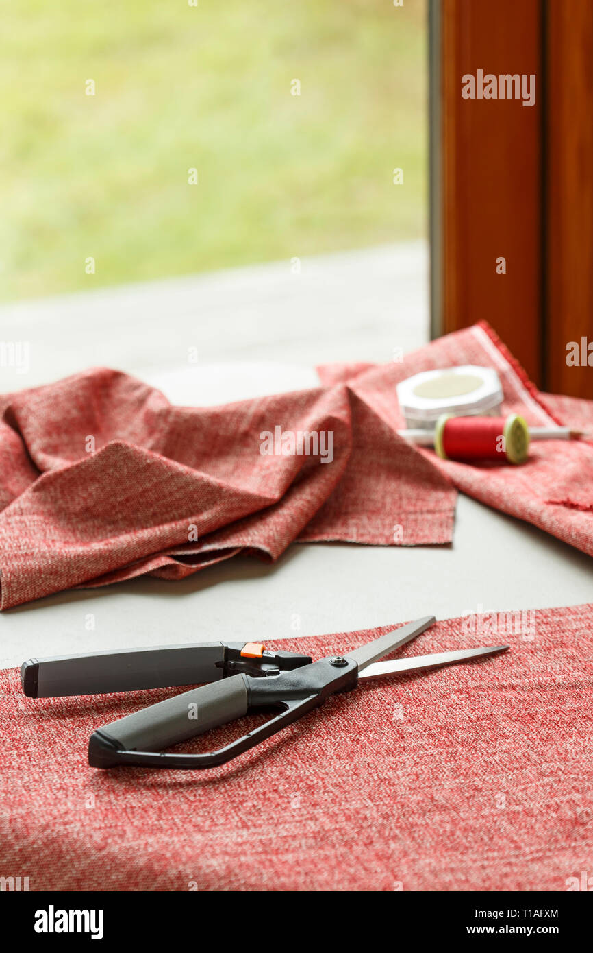 Home cucire bricolage hobby. Tessuto tessuto, forbici e filettatura sul tavolo. Foto Stock