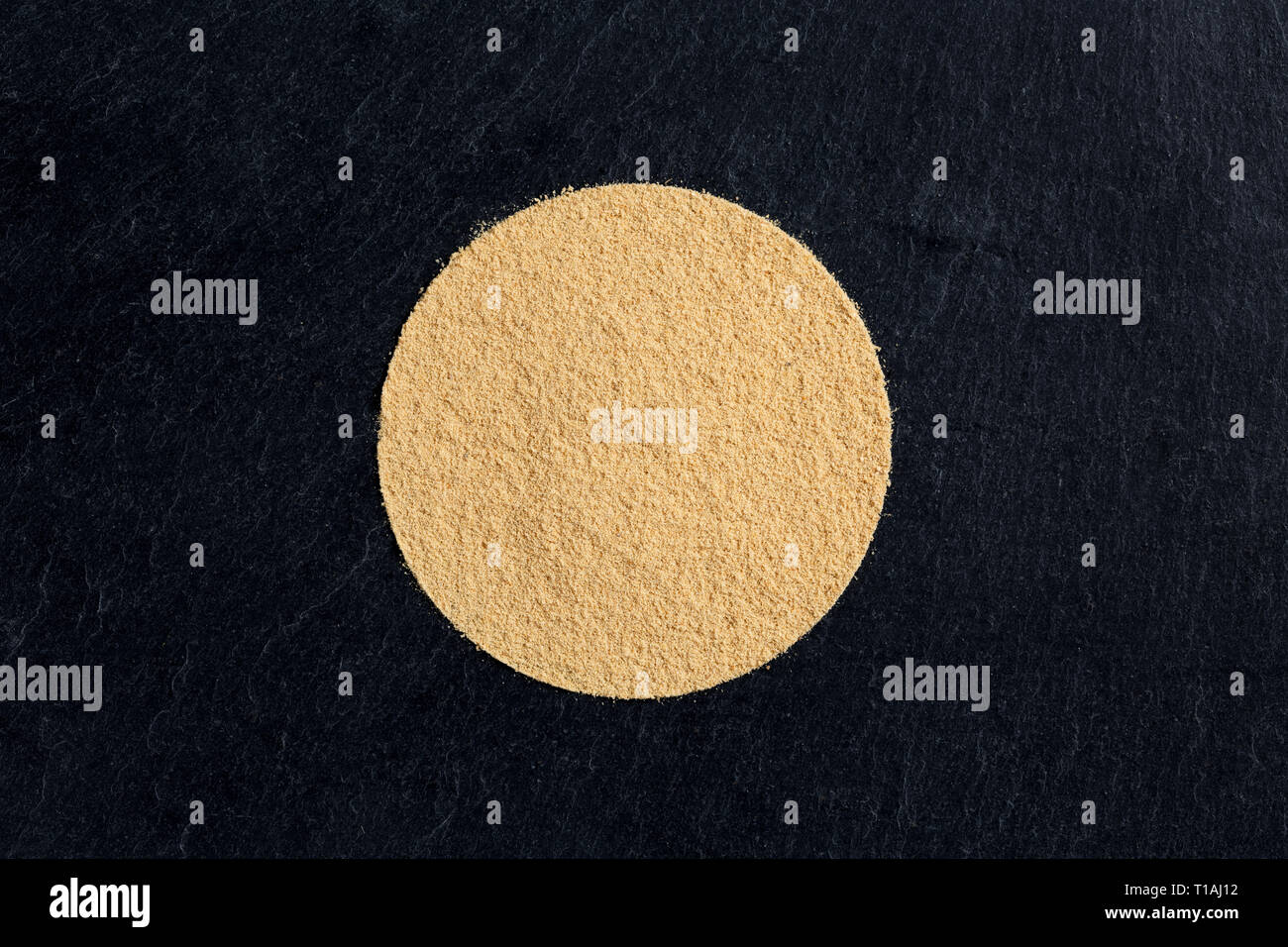 Heap circolare di zenzero in polvere in nero ardesia sfondo, vista da sopra Foto Stock