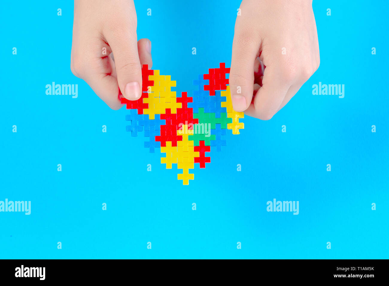 Bambino mano azienda cuore colorati su sfondo blu. Mondo autismo consapevolezza giorno di concetto Foto Stock