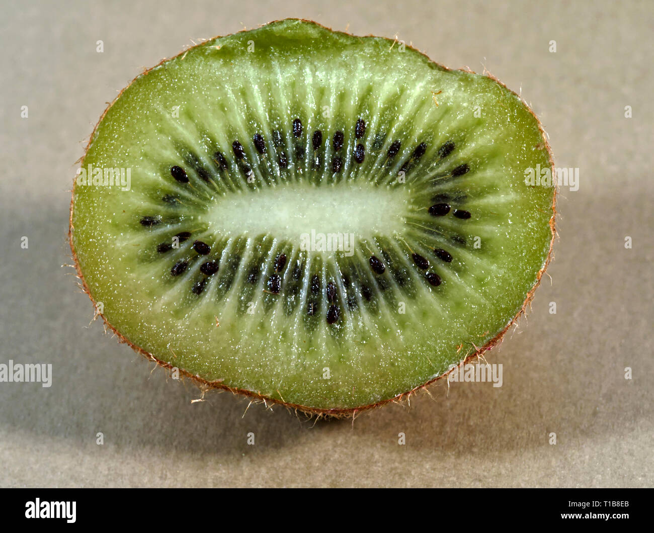 Close-up di un kiwi tagliate a metà che mostra una sezione trasversale attraverso il nucleo del sia con carne e semi visibile. Foto Stock