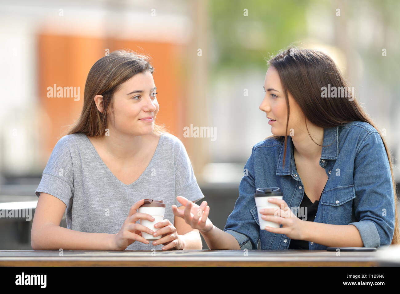 Due amici casual parlando in un parco di bere il caffè Foto Stock