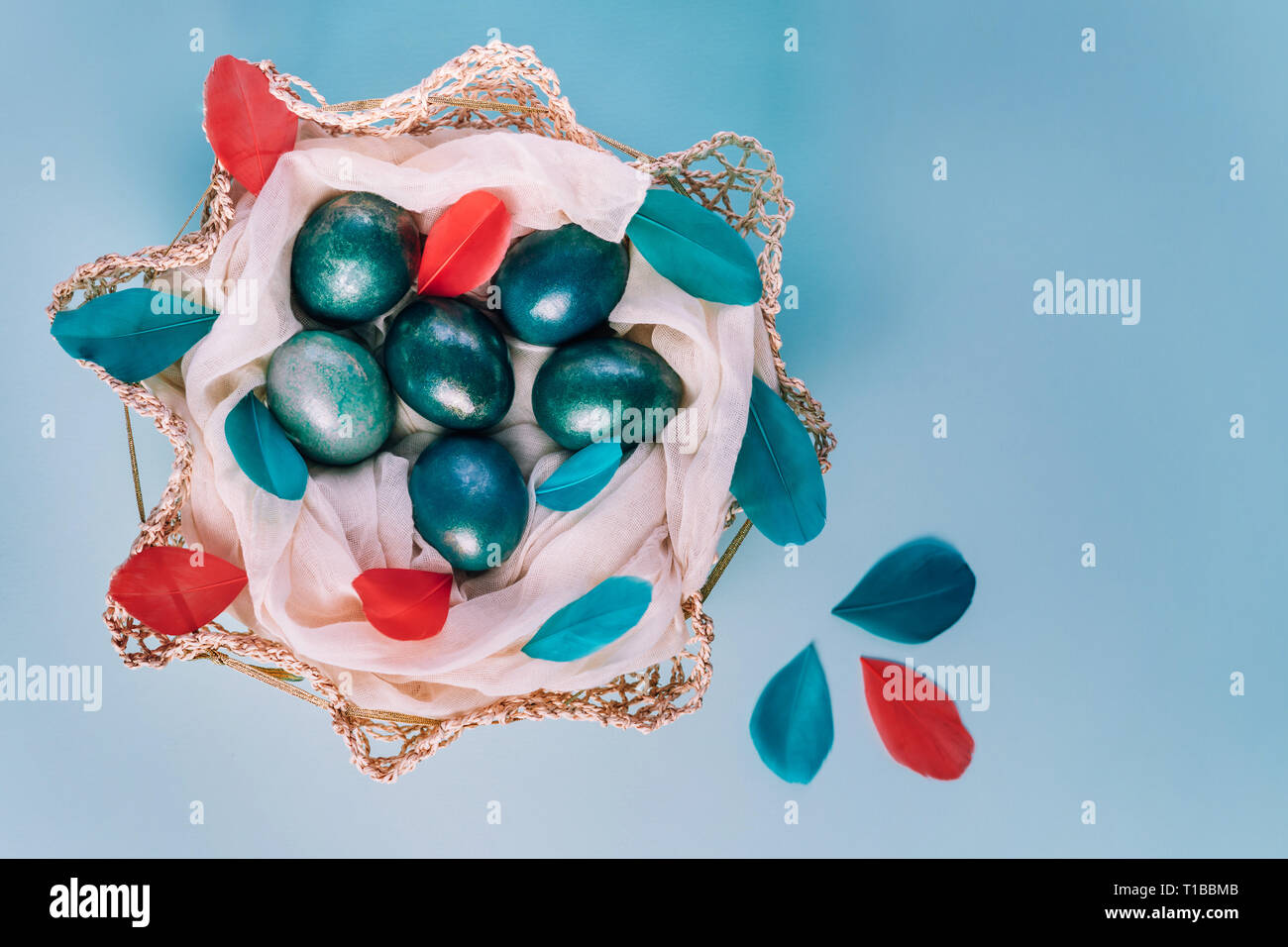 Sfondo di pasqua con uova decorate in blu, turchese e oro nel nido con le piume colorate. Vista dall'alto. Copia dello spazio. Foto Stock